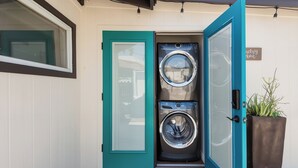 A laundry room with two washing machines, a teal door, and a sign that says "Laundry Room". - Visit Sports and Culture Venues from an Artful Garden Studio in Central Phoenix (Phoenix)