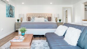 A modern bedroom with a large bed, a blue sofa, and a wooden coffee table. - Visit Sports and Culture Venues from an Artful Garden Studio in Central Phoenix (Phoenix)