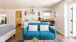 A modern apartment with a blue sofa, a bed, a kitchen, and a dining area. - Visit Sports and Culture Venues from an Artful Garden Studio in Central Phoenix (Phoenix)