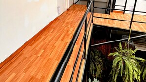 A room with a wooden floor, a window, a door, and a staircase with a metal railing. - Samanai Wasi Hostel  (Lima)