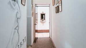 A hallway with a large mural on the left, framed pictures on the walls, and a door at the end leading to another room. - Samanai Wasi Hostel  (Lima)