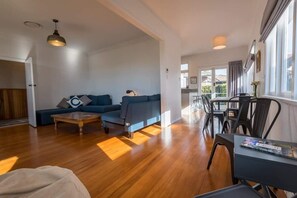 Ein modernes Wohnzimmer mit einer Couch, einem Couchtisch und einem Essbereich mit Stühlen.
