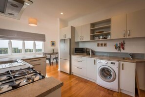 Une cuisine moderne équipée d’une cuisinière à gaz, d’un four à micro-ondes, d’un réfrigérateur et d’un lave-linge.