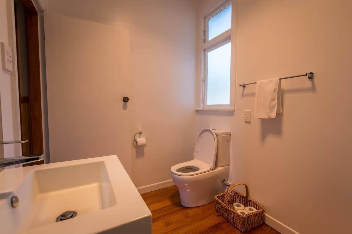 A bathroom with a white sink, toilet, and a window.
