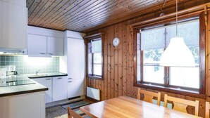 A kitchen with white cabinets, a wooden table, and a window with a clock. - Amazing home in Sysslebäck with kitchen (Sysslebäck)