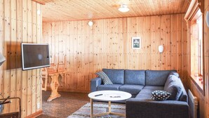 A cozy room with a wooden interior, a gray sofa, a round coffee table, and a mounted TV. - Amazing home in Sysslebäck with kitchen (Sysslebäck)