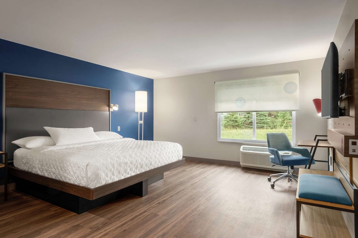 Una habitación de hotel moderna con una cama grande, un escritorio y una silla.