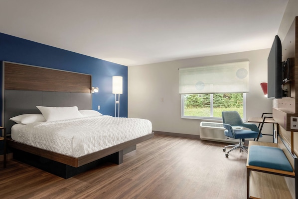 A modern hotel room with a large bed, a desk, and a chair.
