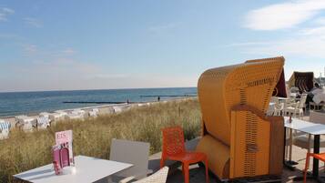 Ein Restaurant direkt am Strand mit Korbmöbeln und Meerblick.