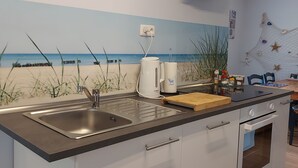 A kitchen with a view of the beach, a coffee maker, and a cutting board. - Vacation home at the edge of the forest Biendorf near Kühlungsborn - 2-room vacation home (70m², max. (Biendorf)