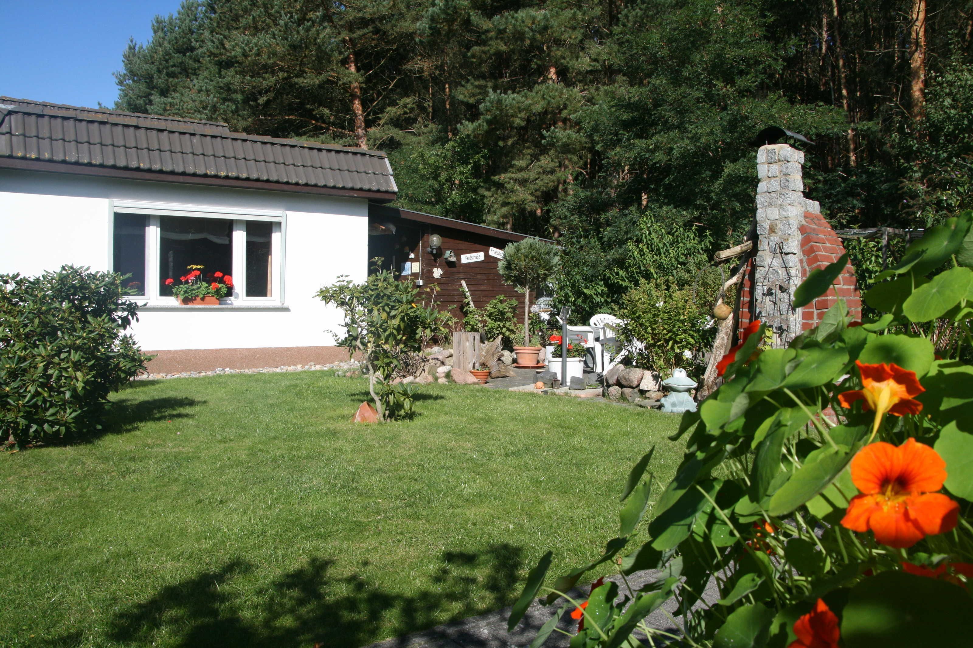 Una casita con fachada blanca, techo rojo y chimenea de piedra.