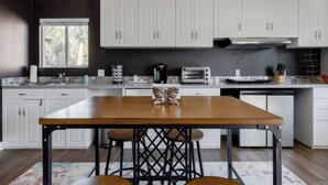 A modern kitchen with white cabinets, a wooden table, and a window. - Stay Close to Culture & Sports Venues in a Spacious & Stylish Butterfly Studio (Phoenix)