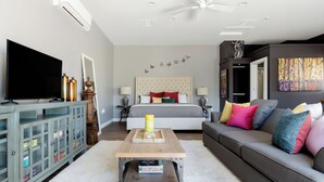 A modern bedroom with a bed, a TV, a wooden coffee table, a grey sofa, and a wardrobe. - Stay Close to Culture & Sports Venues in a Spacious & Stylish Butterfly Studio (Phoenix)