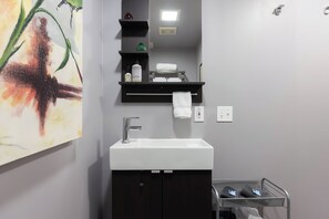 A modern bathroom with a white sink, dark cabinets, a mirror, and a towel rack. - Stay Close to Culture & Sports Venues in a Spacious & Stylish Butterfly Studio (Phoenix)