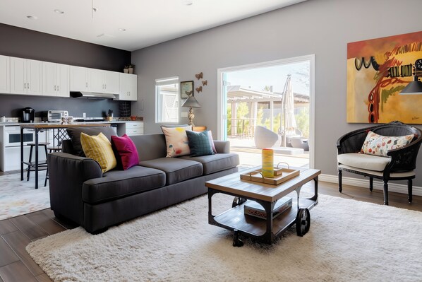 A modern living room with a dark grey sofa, a coffee table, and a white shag rug. - Stay Close to Culture & Sports Venues in a Spacious & Stylish Butterfly Studio (Phoenix)