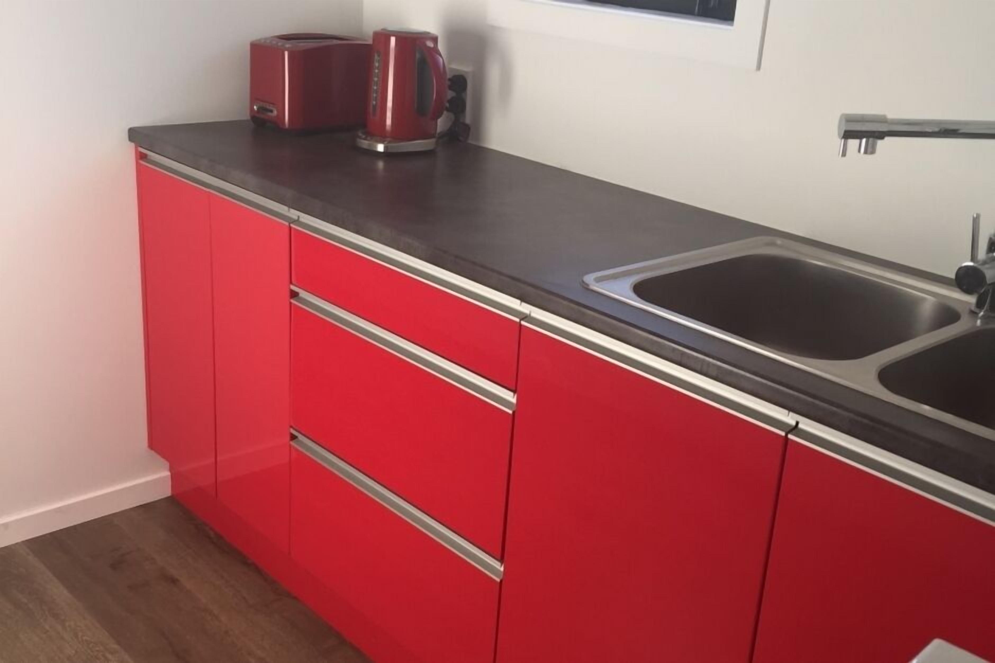 A kitchen with red cabinets and a stainless steel sink.