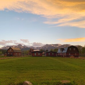 Un entorno rural con varias edificaciones de madera y un extenso campo abierto.
