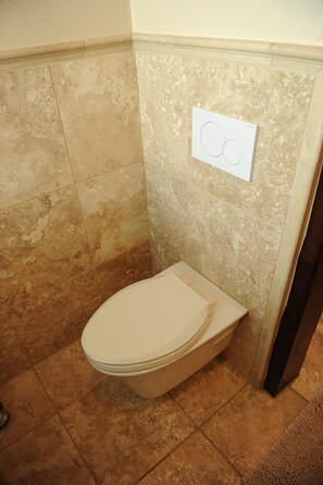Un baño con inodoro, paredes con azulejos y un perchero para toallas.