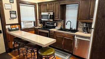 Una cocina con armarios de madera, encimera de granito, refrigerador de acero inoxidable y microondas empotrado.