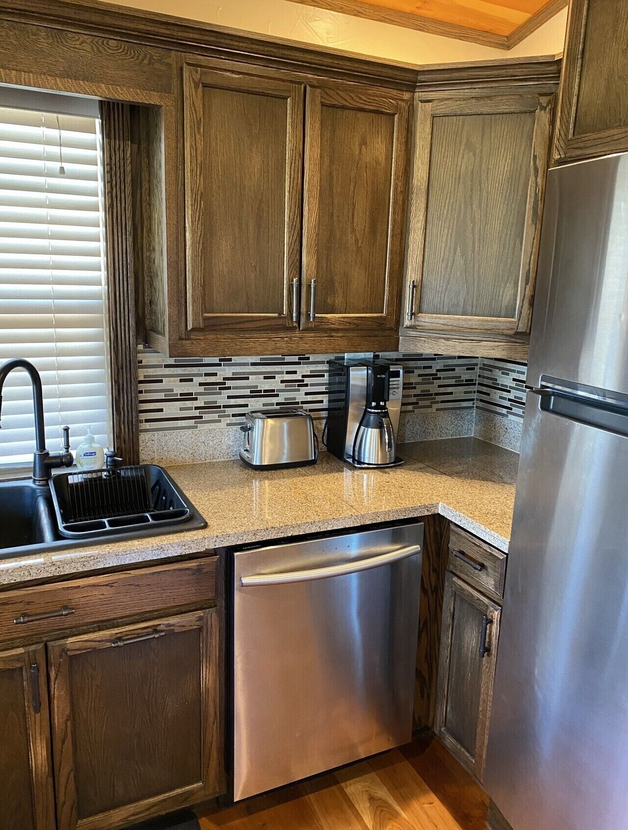 A kitchen with wooden cabinets, a stainless steel dishwasher, and a coffee maker.