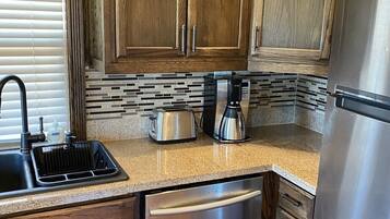 A kitchen with wooden cabinets, a stainless steel dishwasher, and a coffee maker.