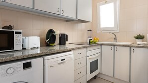 A modern kitchen with white cabinets, a microwave, a coffee maker, and a sink.