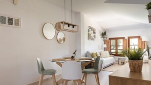 A modern kitchen with a dining table, chairs, and a hanging light fixture.