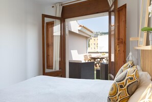 Quarto com cama, janela e vista para a área da varanda.