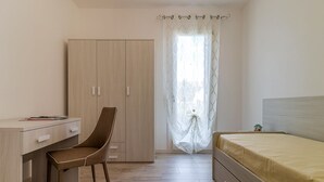 A bedroom with a bed, a desk with a chair, a wardrobe, and a window with curtains. - The Romeo country house apartment accommodates up to 5 people (4 + 1) (Cimadolmo)