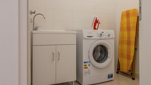 A compact laundry area with a washing machine, a sink, and a drying rack. - The Romeo country house apartment accommodates up to 5 people (4 + 1) (Cimadolmo)