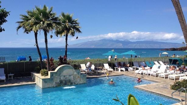 A pool area with lounge chairs and umbrellas, overlooking a beach and ocean. - Tower 1 South facing. Beautiful Ocean, Lanai , koi pond and courtyard views (Lahaina)