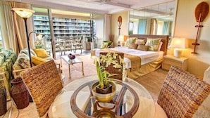 A hotel room with a large bed, a sitting area with a round table, and a view of a balcony with a library. - Tower 1 South facing. Beautiful Ocean, Lanai , koi pond and courtyard views (Lahaina)