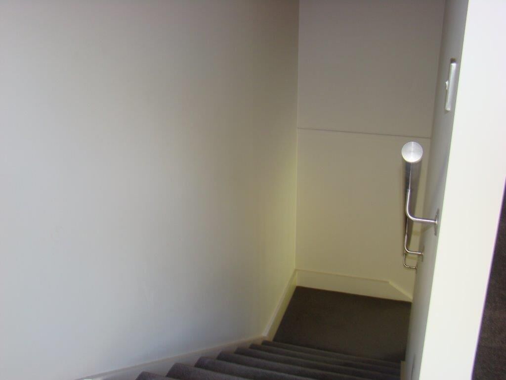 Una escalera con barandilla y una puerta al final.