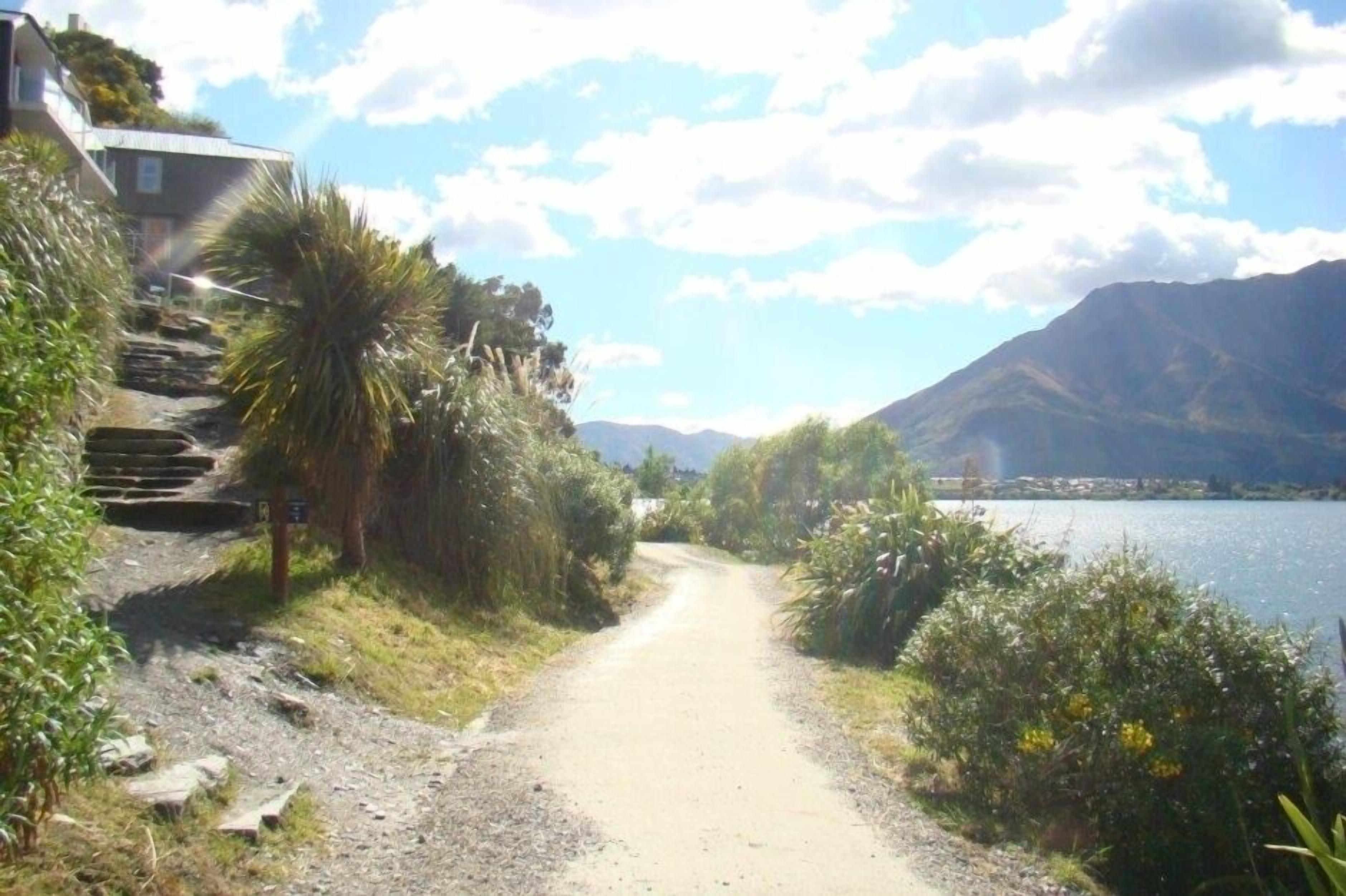 Un sentiero sterrato che conduce a un lago, con montagne sullo sfondo.