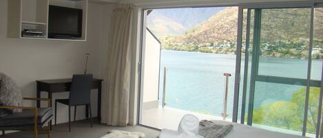Une chambre d’hôtel avec un lit, un bureau, une chaise et une vue sur un lac.