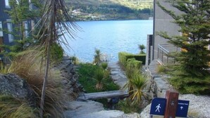 A stone staircase leading to a balcony overlooking a lake, with a sign indicating the Franklin Track. - 3 LEVEL LAKESIDE LUXURY WITH MAGNIFICENT LAKE & MOUNTAIN VIEWS POTENTIAL CARHIRE (Frankton)
