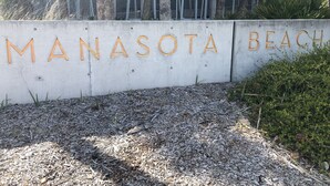 Schild für Manasota Beach mit einer Betonmauer und Holzbuchstaben.
