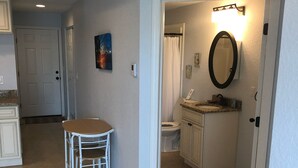 Ein geräumiger Wohnbereich mit Esstisch und Stühlen, eine Küche mit weißen Schränken sowie ein Badezimmer mit Toilette und Waschbecken.