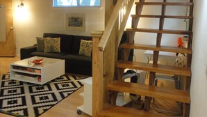 A loft-style living space with a wooden staircase, a sofa, a coffee table, and a patterned rug. - Best Central Location/Private Urban Oasis/ Travis Heights Near SoCo & Downtown (Austin)