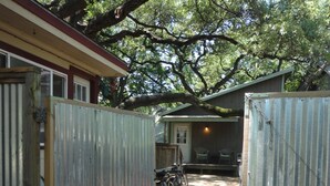 A gated property with a covered outdoor area, a bicycle, and a building with a window and door. - Best Central Location/Private Urban Oasis/ Travis Heights Near SoCo & Downtown (Austin)