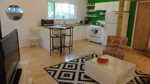 A compact kitchen with white cabinets, a microwave, and a sink. There's a patterned rug on the floor and a white coffee table with a red object on it. - Best Central Location/Private Urban Oasis/ Travis Heights Near SoCo & Downtown (Austin)