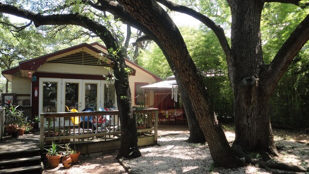 A rustic wooden house with a porch, surrounded by large trees and potted plants. - Best Central Location/Private Urban Oasis/ Travis Heights Near SoCo & Downtown (Austin)