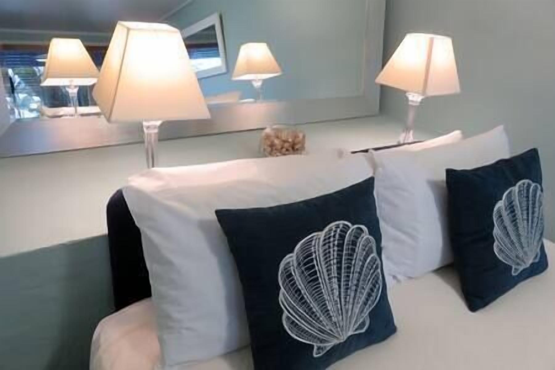 Une chambre d’hôtel avec un lit, deux lampes, un miroir et des coussins décoratifs.