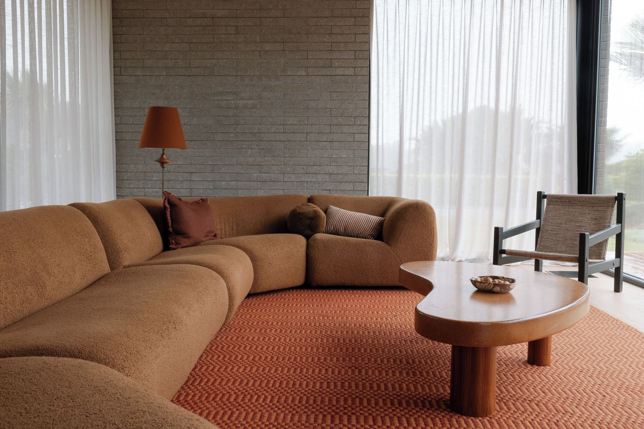 A modern living room with a sectional sofa, a round coffee table, and a chair.