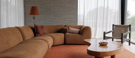 A modern living room with a sectional sofa, a round coffee table, and a chair.