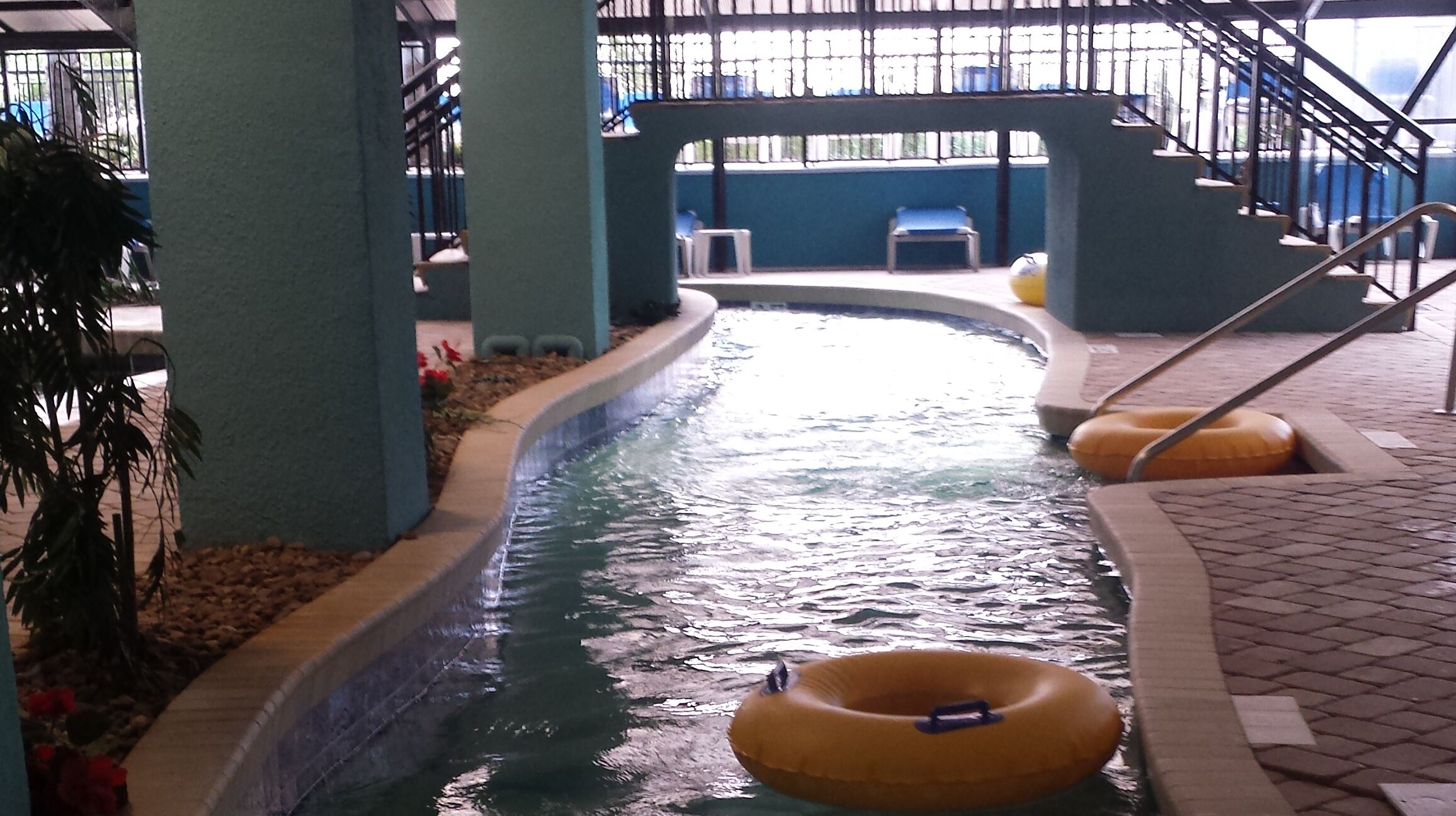 Eine Indoor-Wasserrutsche mit gelben Ringen, ein Schwimmbecken und eine Treppe.
