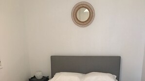 A neatly made bed with white linens, a grey headboard, and a round mirror on the wall. - PIEDS DANS L’EAU, Sevrier, Maison, Accès privé lac et ponton. Idyllique, 6Pers (Sévrier)
