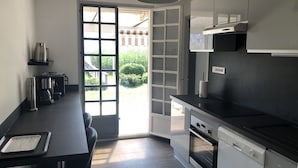 A modern kitchen with a black countertop, stainless steel appliances, and a large window. - PIEDS DANS L’EAU, Sevrier, Maison, Accès privé lac et ponton. Idyllique, 6Pers (Sévrier)