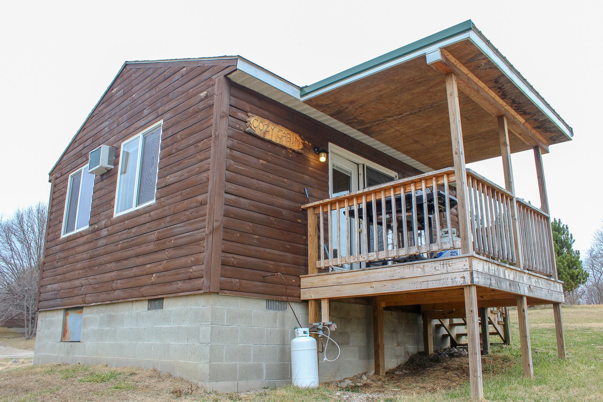 A wooden cabin with a balcony and a small attached structure.