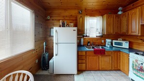 Eine kompakte Küche mit Holzschränken, einem Kühlschrank, einer Mikrowelle und einem Herd.